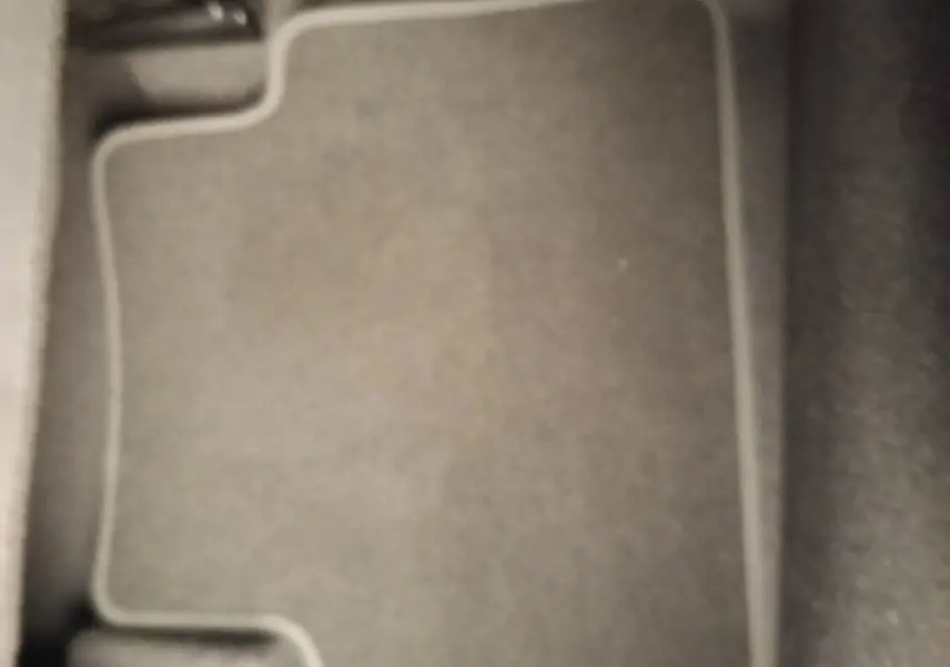 Vue rapprochée du tapis de sol gris foncé à l'avant droit du Nissan Juke DIG-T 114 BVM6 N-Connecta 2025.
