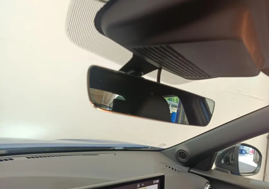 Vue intérieure du tableau de bord et rétroviseur d’un Nissan Juke bleu 2025 avec écran tactile et volant multifonctions.