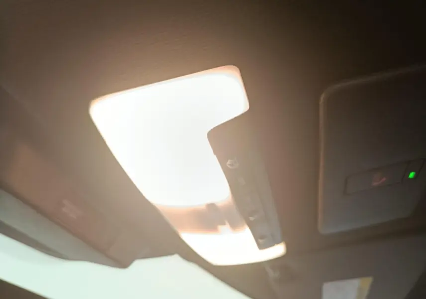 Plafonnier intérieur allumé du Nissan Juke bleu, vue en léger contre-plongée vers l'avant du toit.