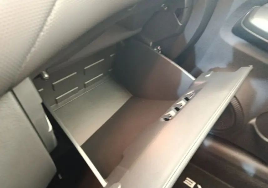 Vue rapprochée de la boîte à gants ouverte côté passager du Nissan Juke bleu 2025, intérieur noir.