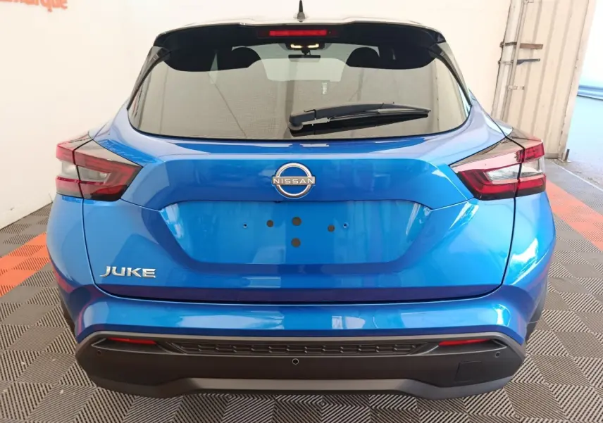 Vue arrière d'un Nissan Juke bleu 2025 avec feux LED et hayon noir brillant dans un garage.