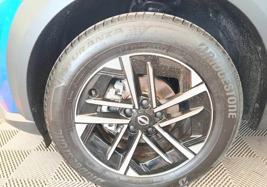 Gros plan sur la roue avant droite du Nissan Juke bleu 2025 avec jante alliage noire et argentée, pneu Bridgestone.