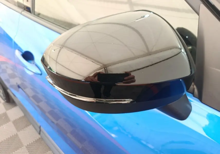 Gros plan sur le rétroviseur droit noir avec clignotant intégré du Nissan Juke bleu 2025 côté conducteur.