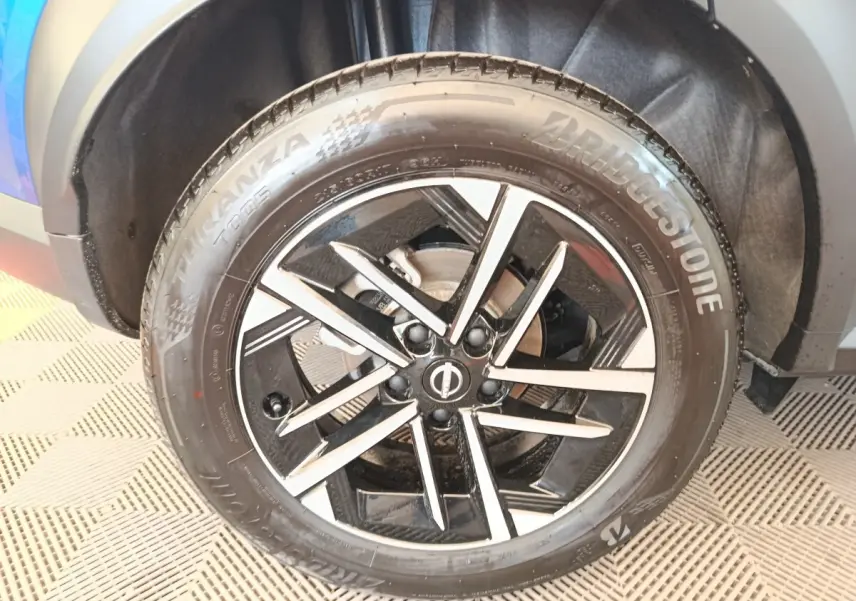 Gros plan sur la roue avant gauche du Nissan Juke bleu, avec jante alliage noire et argentée au design moderne.