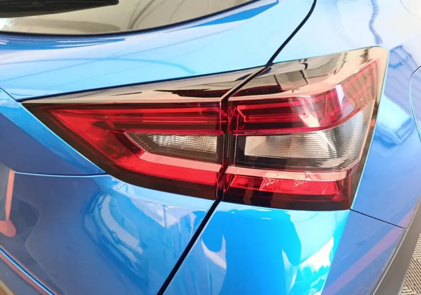 Gros plan sur le feu arrière droit rouge du Nissan Juke bleu 2025, soulignant la carrosserie brillante.
