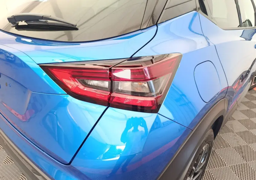 Vue 3/4 arrière droite du Nissan Juke bleu mettant en valeur le feu arrière et la trappe à carburant.
