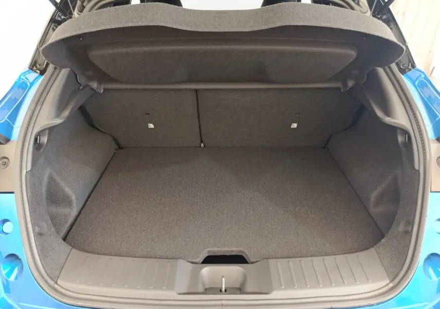 Coffre ouvert vu de l'arrière d'un Nissan Juke bleu 2025, montrant l'espace de chargement vide et la garniture intérieure grise.
