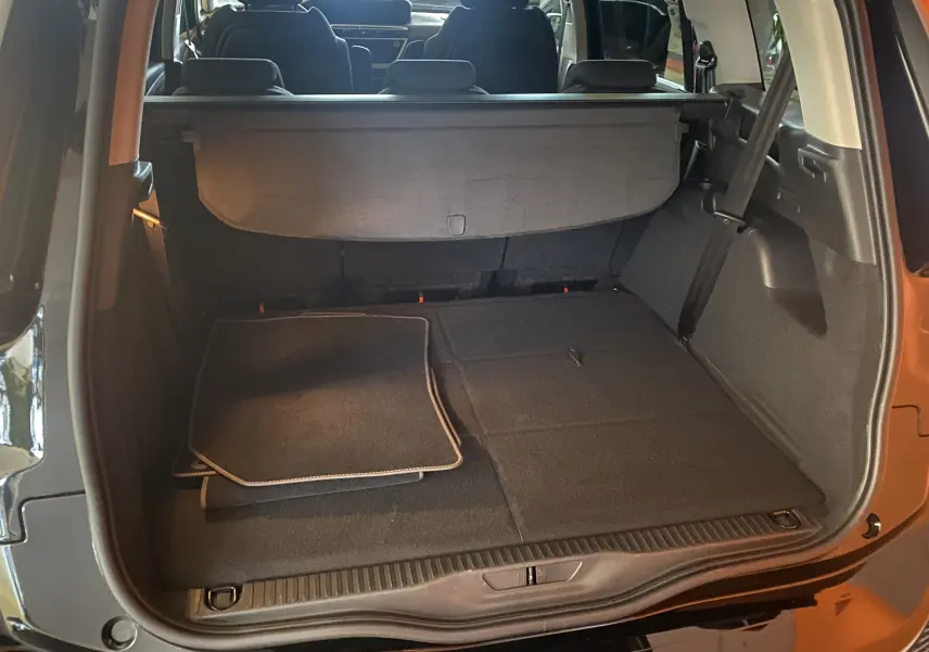 Coffre ouvert vu de l'arrière d'un Citroën Grand C4 Spacetourer noir Perla avec tapis et cache-bagages déployé.