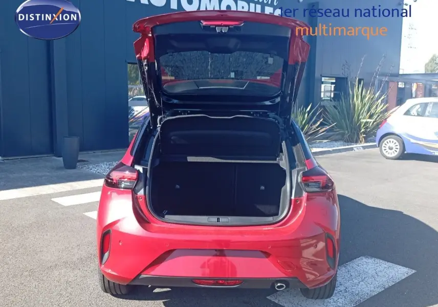 Vue arrière d’une Opel Corsa rouge Kardio métal avec toit noir, coffre ouvert montrant l’espace de chargement.