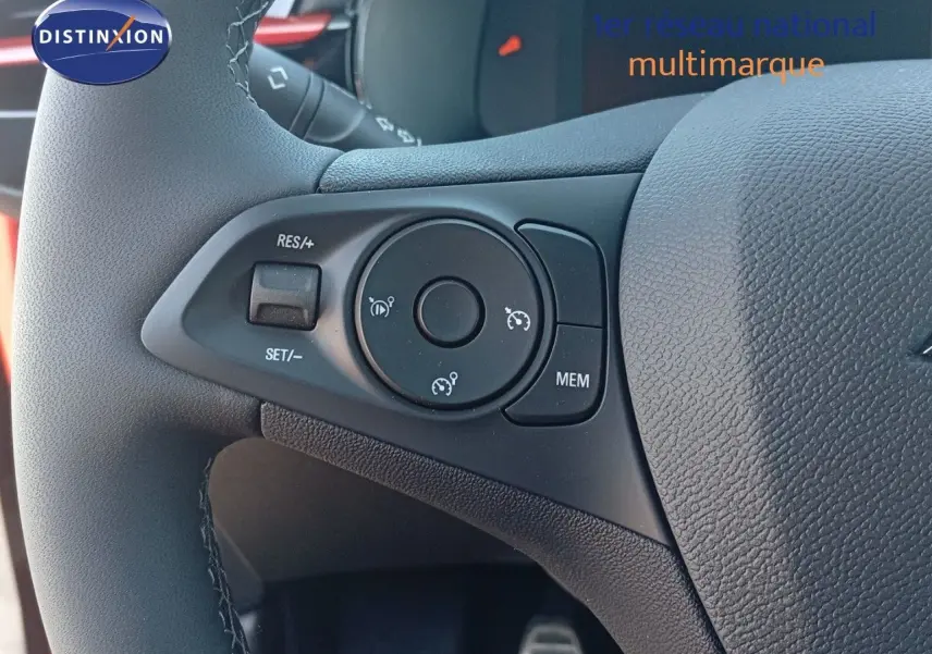 Gros plan sur les commandes au volant de l’Opel Corsa 2023, avec cuir noir et détails rouges visibles en arrière-plan.