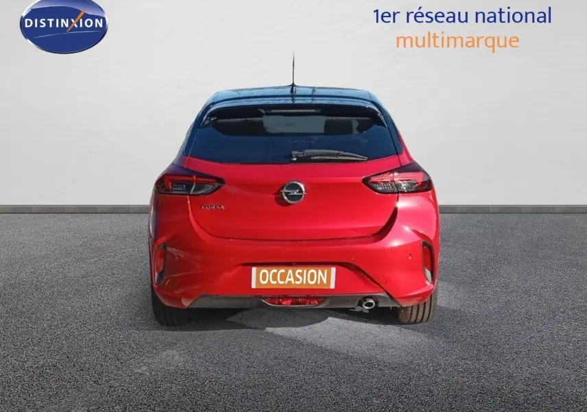 Vue arrière d'une Opel Corsa rouge Kardio métal avec toit noir, affichant la plaque "OCCASION" sur un sol gris.