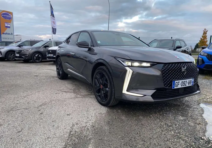 DS4 gris platinium vue 3/4 avant droit, avec calandre distinctive et feux LED en forme de flèche.