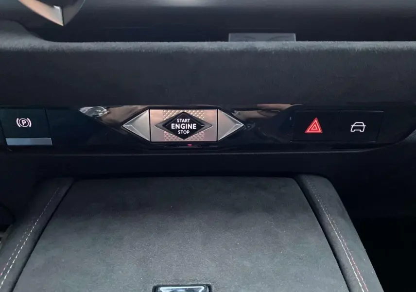 Détail du tableau de bord du DS4 2022 avec bouton start/stop central et commandes électroniques sur fond noir.