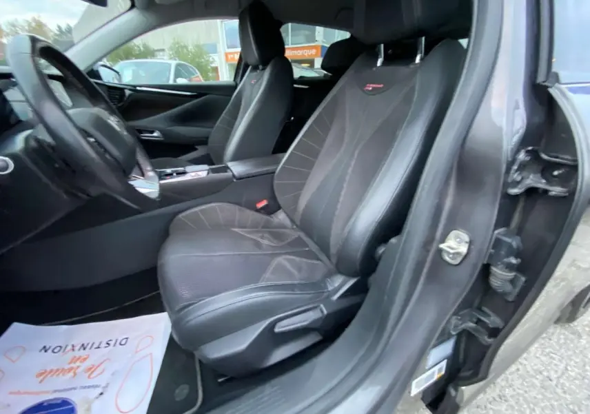 Vue intérieure côté conducteur du DS4 2022 gris platinium, mettant en valeur les sièges sport en cuir noir avec surpiqûres rouges.