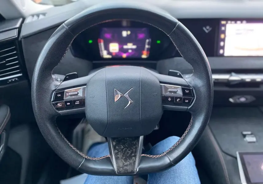 Volant en cuir noir avec logo DS au centre, tableau de bord numérique et écran tactile dans l'habitacle du DS4 gris platinium 2022.