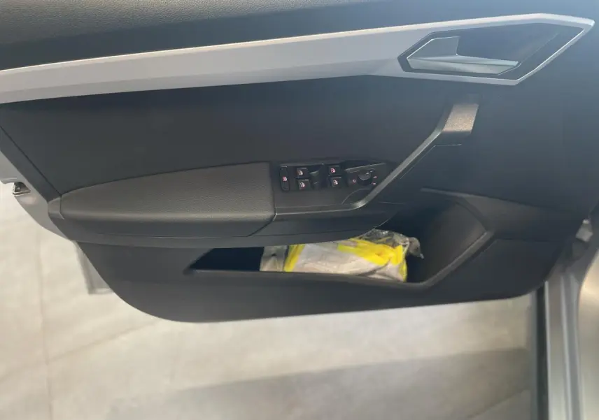 Vue rapprochée de la porte avant gauche du SEAT Arona 2024, avec commandes de vitres et rangement noir.