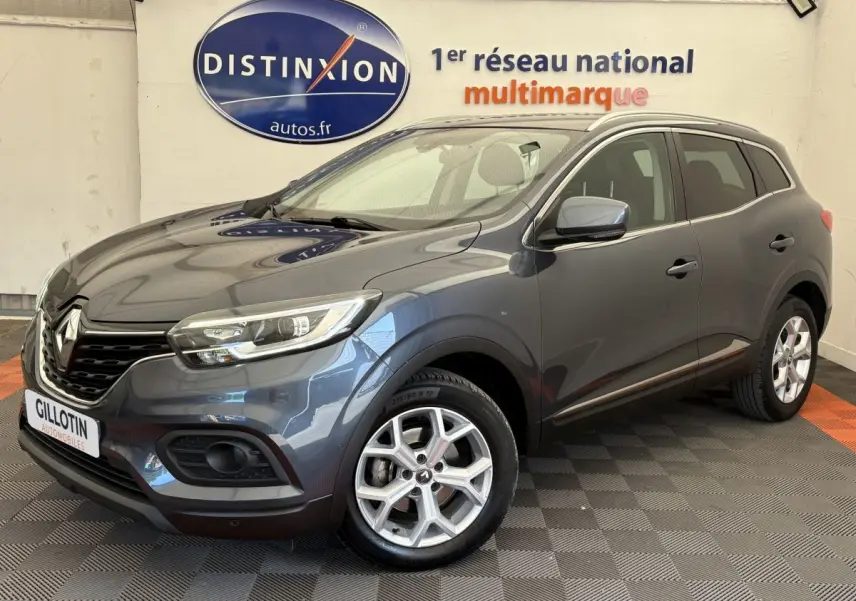Renault Kadjar Intens gris foncé vu en 3/4 avant droit dans un showroom avec logo Distinxion en arrière-plan.