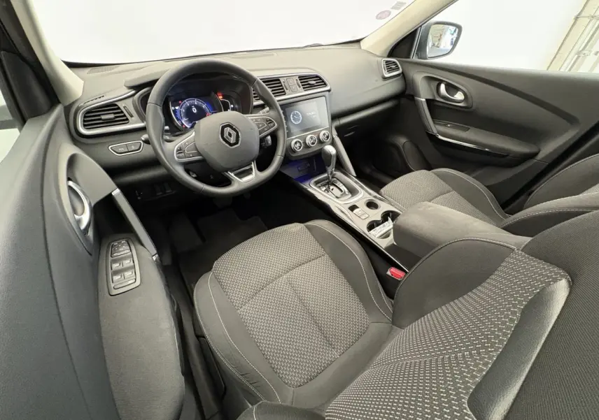 Intérieur avant Renault Kadjar gris, vue côté conducteur, tableau de bord avec écran tactile et volant multifonctions.