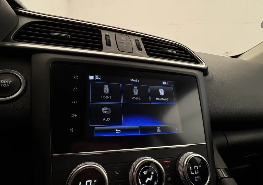 Vue rapprochée de l’écran tactile multimédia et des commandes de climatisation du tableau de bord du Renault Kadjar gris foncé.