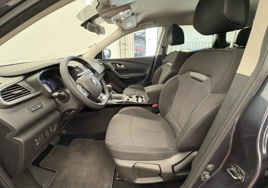 Vue intérieure côté conducteur du Renault Kadjar gris foncé 2019, sièges tissu noir et tableau de bord moderne.