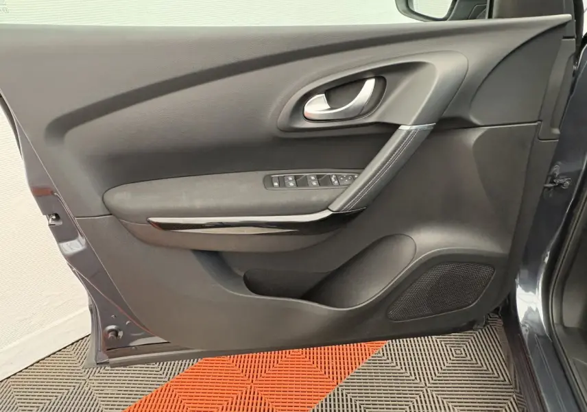 Vue intérieure côté gauche de la porte avant gris foncé du Renault Kadjar avec commandes de vitres et poignée argentée.