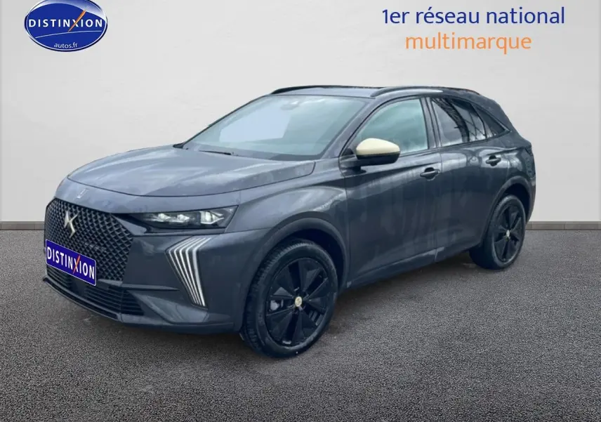 DS7 gris titane en 3/4 avant droit, avec calandre distinctive et jantes noires brillantes.