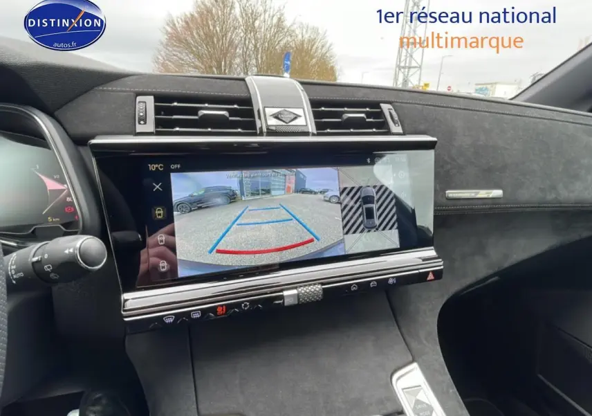Vue intérieure du tableau de bord du DS7 gris titane 2026, écran tactile affichant la caméra de recul et les aides au stationnement.