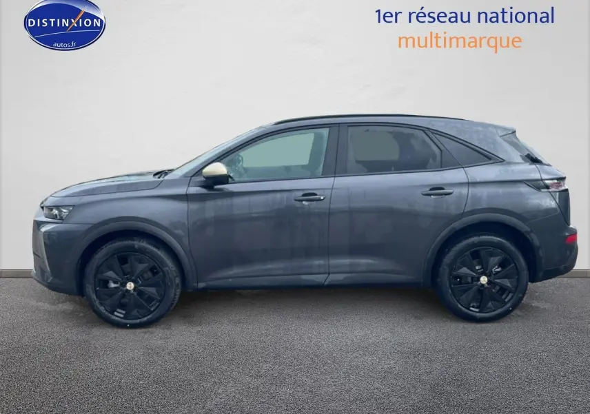 Vue de profil côté gauche d'un DS7 gris titane avec jantes noires et rétroviseur droit beige.