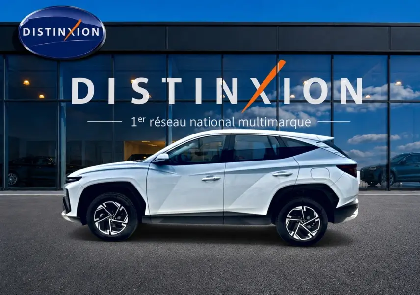 Hyundai Tucson 1.6 t-gdi 239 hybride blanc vu de profil côté gauche devant une vitrine Distinxion.