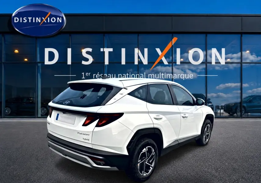 Vue 3/4 arrière droite d'un Hyundai Tucson blanc hybride 2026 avec jantes alliage et feux arrière LED distinctifs.