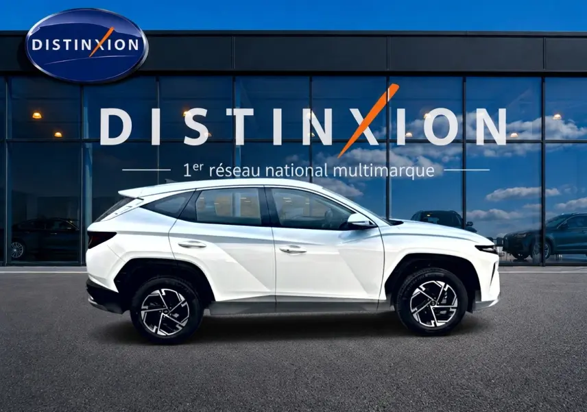 Hyundai Tucson blanc en profil côté gauche, avec jantes alliage noires et détails anguleux modernes.
