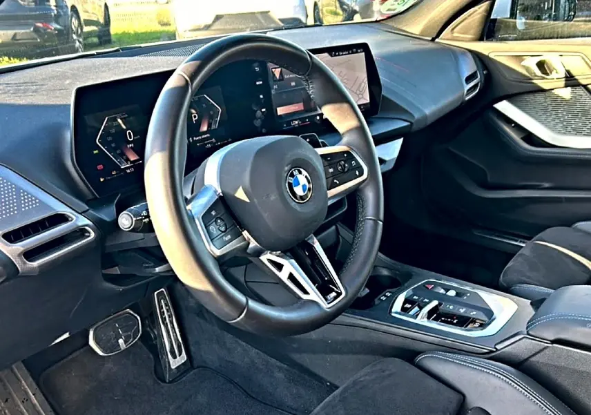 Vue intérieure côté conducteur de la BMW Série 1 2025 avec volant multifonction et tableau de bord digital.