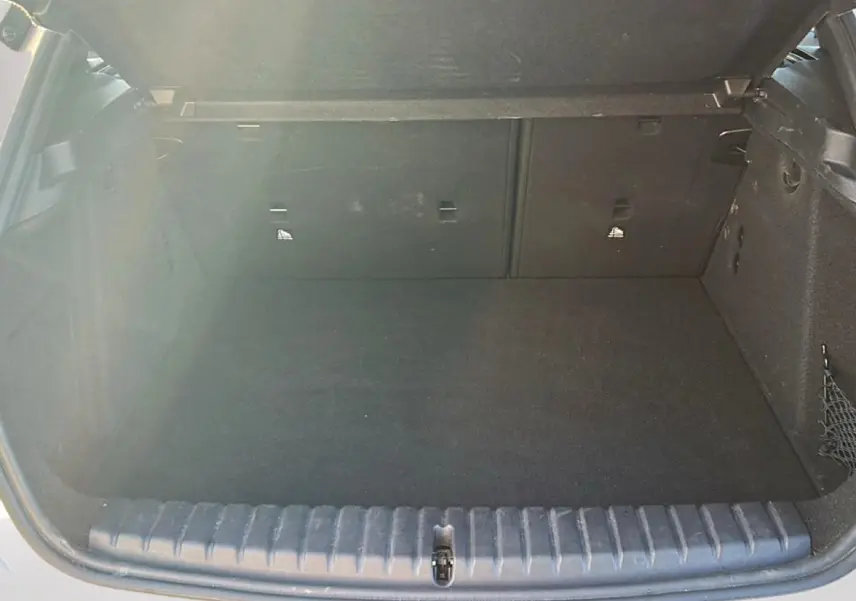Coffre ouvert vu de l'arrière d'une BMW Série 1 blanche, montrant un espace de chargement vide et propre.