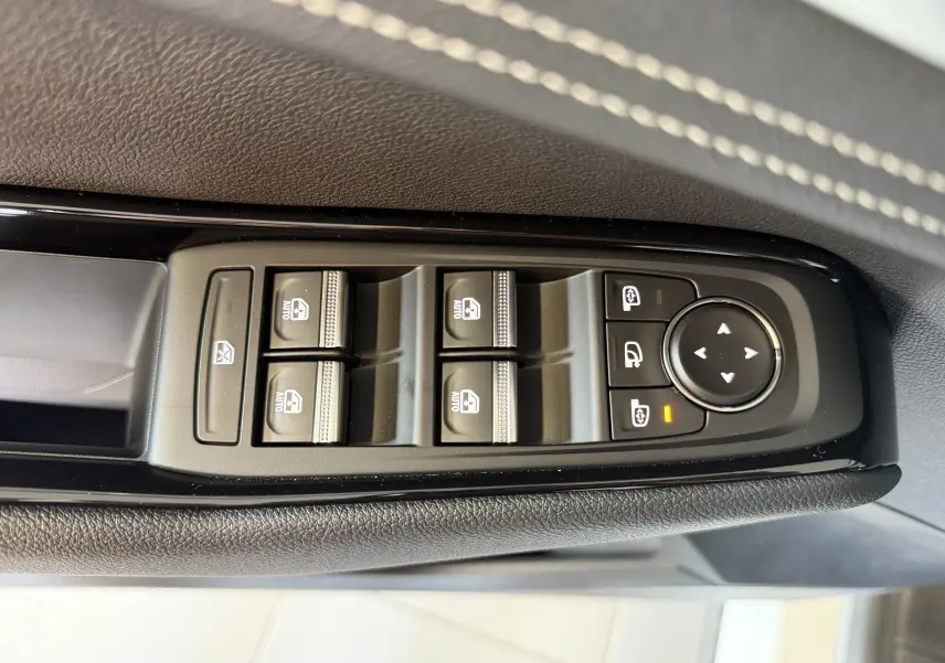 Gros plan sur les commandes des vitres électriques et rétroviseurs sur la porte côté conducteur du Renault Austral blanc toit noir.