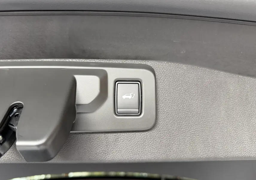 Bouton d'ouverture électrique du coffre sur la garniture intérieure du hayon du Renault Austral blanc toit noir.