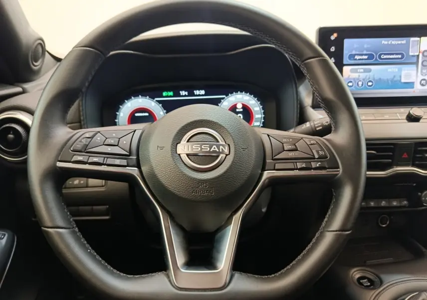 Vue rapprochée du volant noir multifonctions d’un Nissan Juke 2025 avec tableau de bord numérique et écran tactile central.
