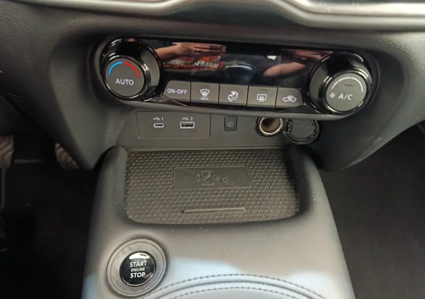 Vue rapprochée de la console centrale noire du Nissan Juke 2025 avec commandes climatisation et ports USB visibles.