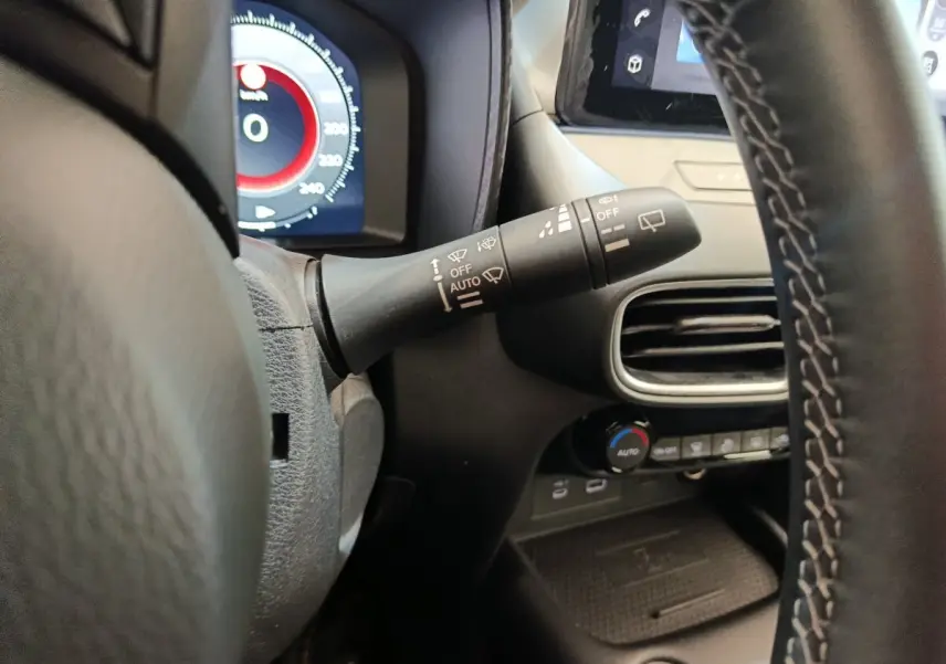 Gros plan sur la manette d'essuie-glace à gauche du volant du Nissan Juke gris clair, tableau de bord partiellement visible.