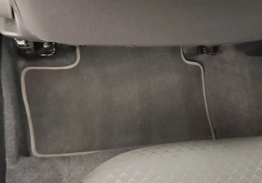 Vue du sol et tapis de sol arrière côté droit du Nissan Juke gris clair 2025, avec partie inférieure du siège visible.