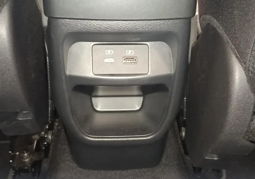 Vue rapprochée de la console centrale arrière du Nissan Juke gris clair, avec prises USB visibles entre les sièges.