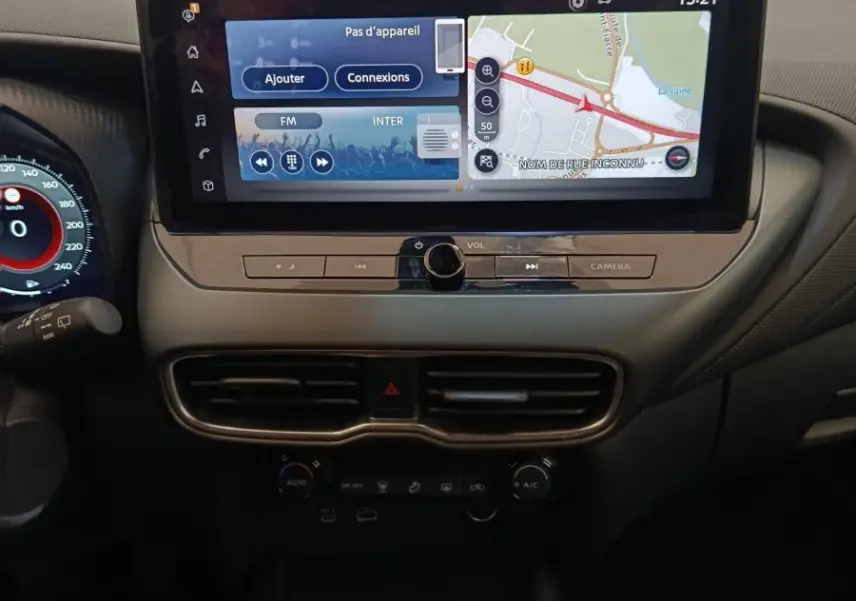 Vue intérieure centrée sur la console centrale du Nissan Juke gris clair 2025 avec écran tactile et levier de vitesses manuel.