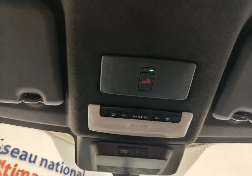 Plafonnier intérieur avec bouton SOS rouge et commandes d’éclairage sur le toit d’un Nissan Juke gris clair 2025.