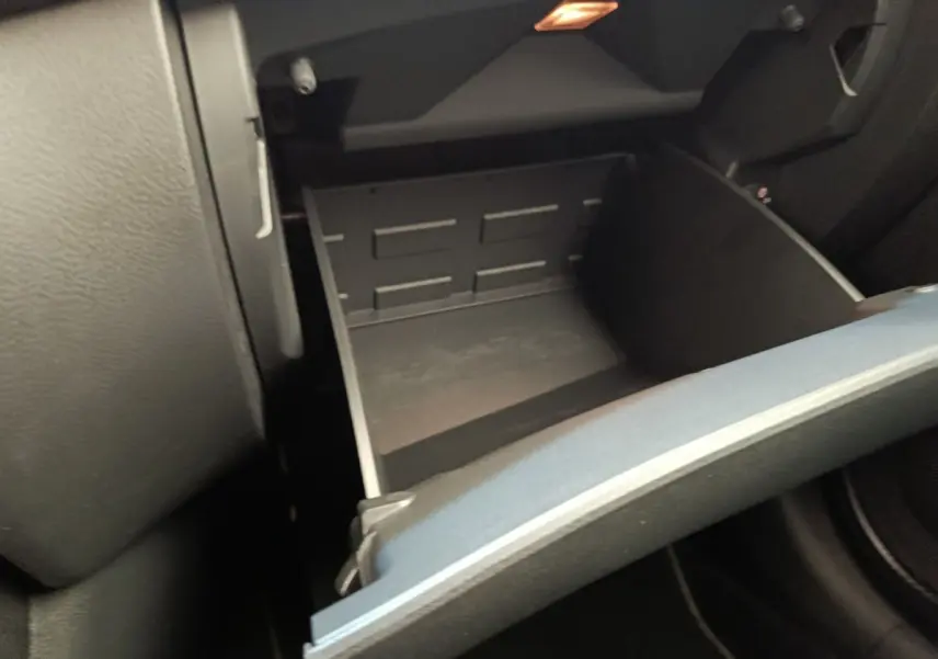 Gros plan sur la boîte à gants ouverte côté passager de l’habitacle d’un Nissan Juke gris clair 2025.