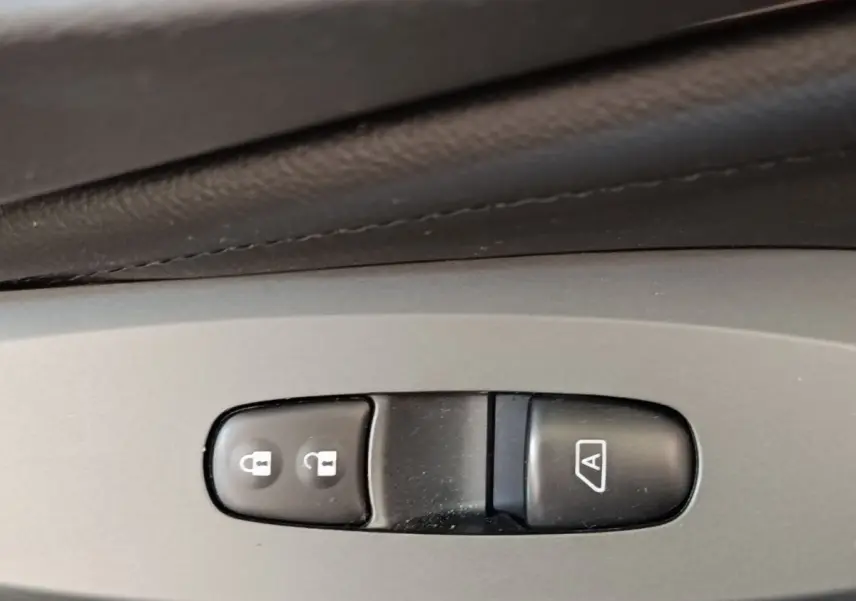 Gros plan sur les boutons de verrouillage centralisé et de lève-vitre automatique dans l'habitacle gris clair du Nissan Juke 2025.