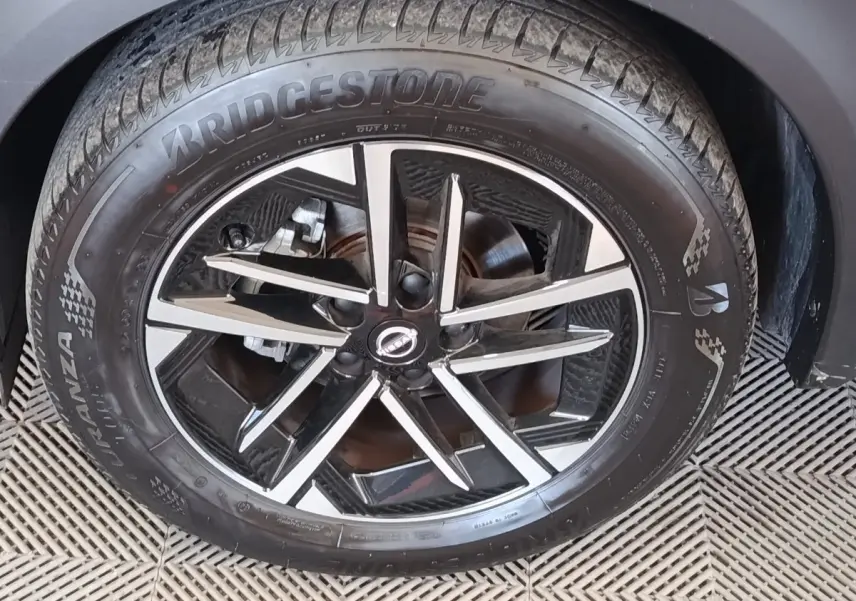 Gros plan sur la roue avant droite du Nissan Juke gris clair avec jante alliage noire et argentée, pneu Bridgestone.