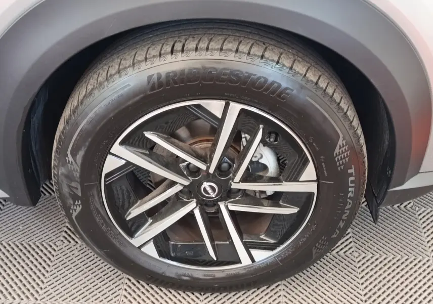 Gros plan sur la roue avant droite du Nissan Juke gris clair, avec jante alliage noire et argentée.
