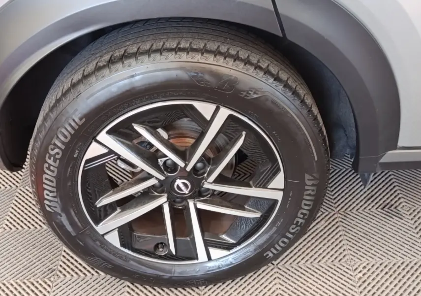 Gros plan sur la roue avant droite gris clair du Nissan Juke 2025 avec jante alliage noire et détails argentés.
