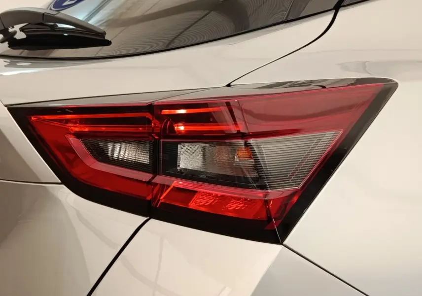 Gros plan sur le feu arrière droit rouge et blanc d’un Nissan Juke gris clair 2025, détails nets et angulaires.