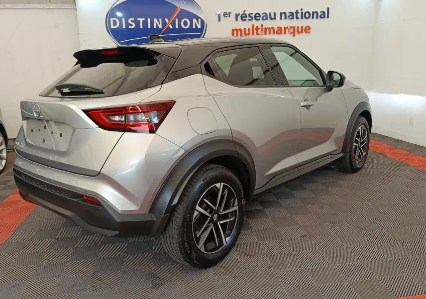 Nissan Juke gris clair vue 3/4 arrière droit, avec jantes alliage noires et toit noir contrasté.