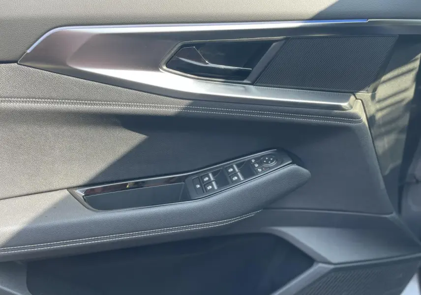 Détail de la porte côté conducteur du Renault Rafale 2025 gris, avec commandes de vitres et surpiqûres blanches.